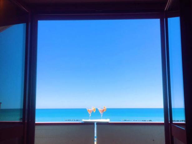 Vista mare da una finestra con due cocktail.