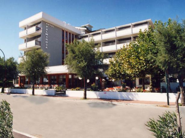 Hotel moderno con balconi e terrazze, circondato da alberi.