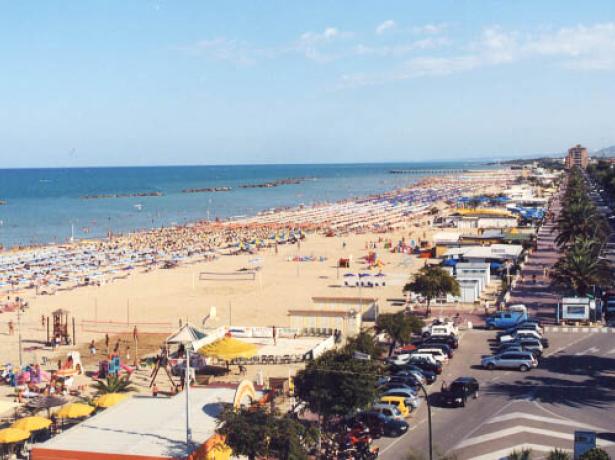 Spiaggia affollata con ombrelloni colorati e mare calmo.